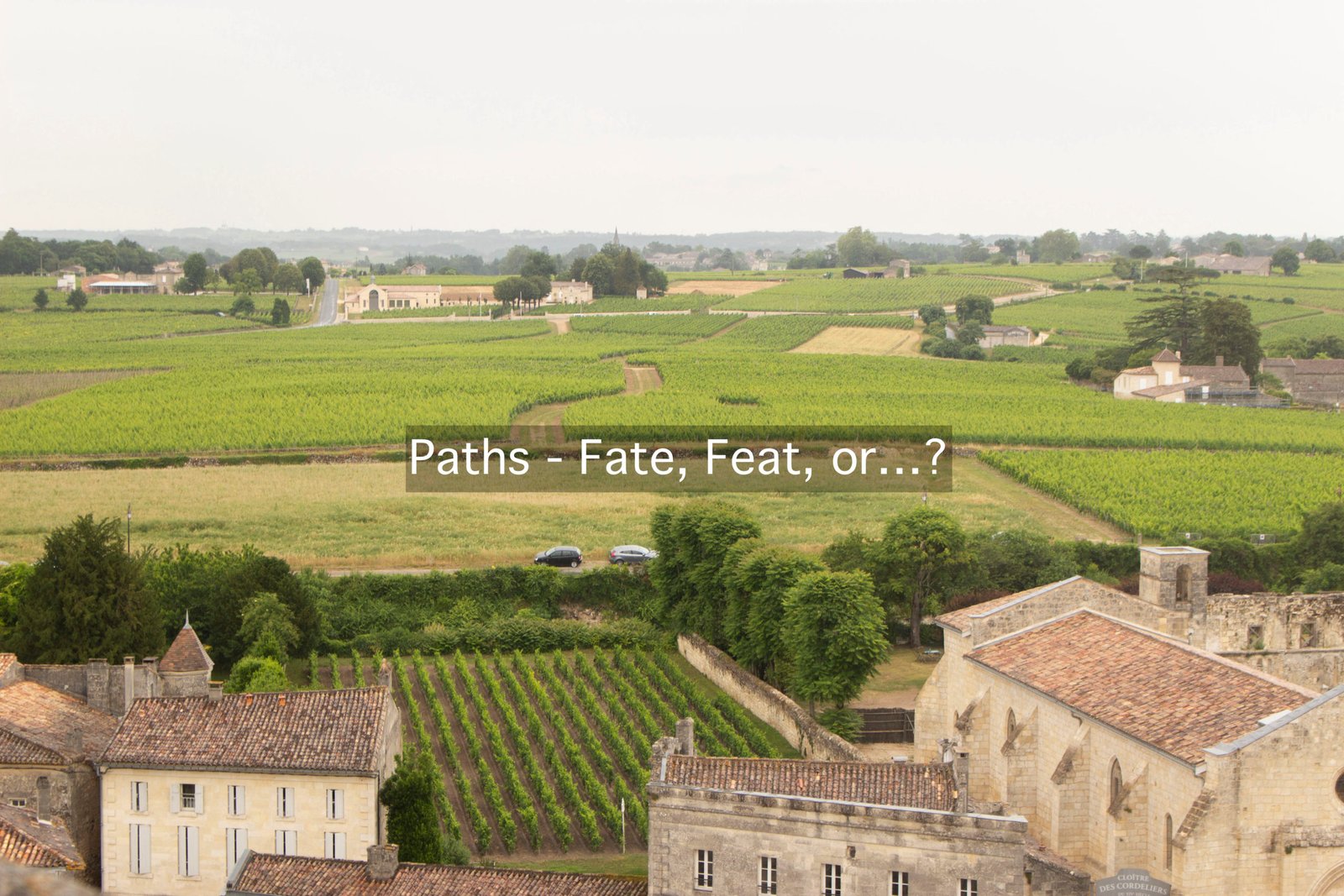 Image shows a small huddle of French houses in front of vast green countryside. Two roads weave out in different directions.