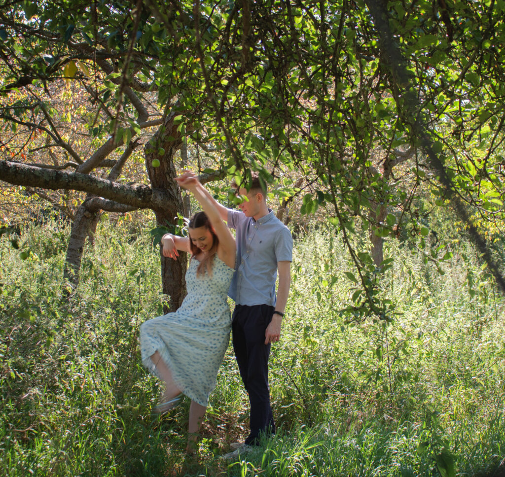 Elegant engagement photo of a romantic couple dancing in woodland together London countryside. 