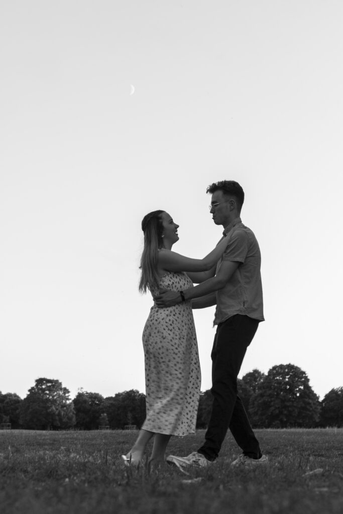 Beautiful, intimate engagement photo of a couple embracing in a scenic meadow in Edinburgh. Celebrate your love with affordable, professional engagement photography by Eleanor Hyde at DistinctiveMode Edinburgh.