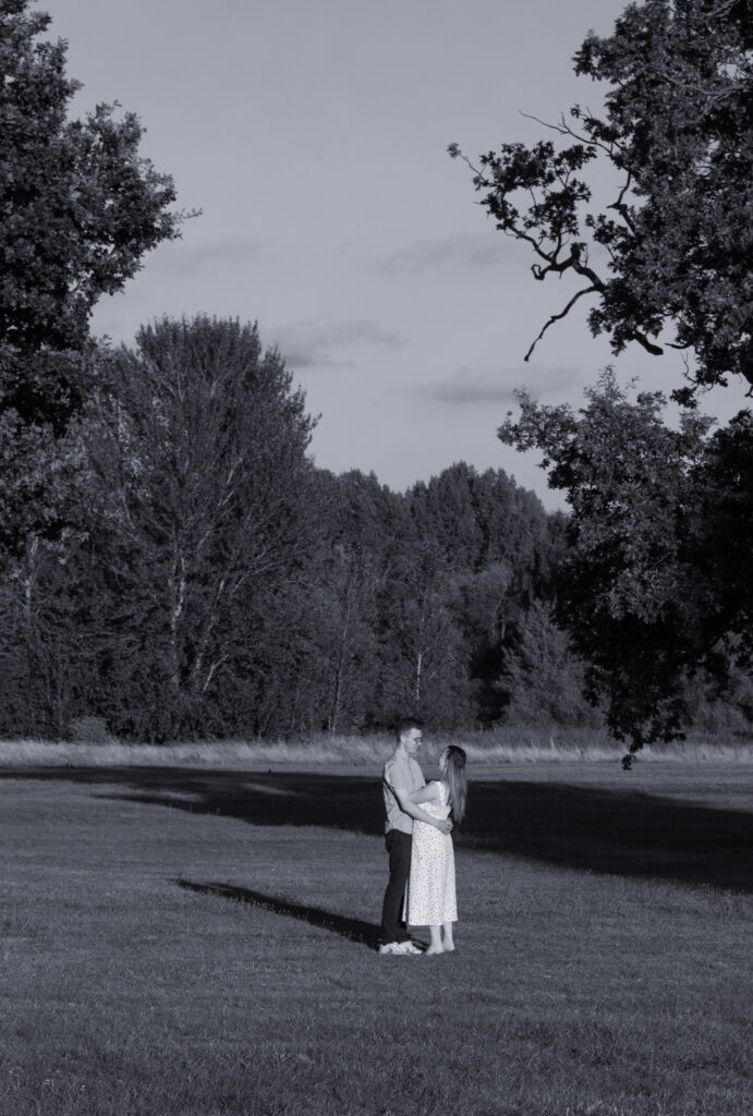 Elegant engagement photo of a couple dancing together outdoors at sunset in London countryside, captured in black and white. Affordable wedding and engagement photography by Eleanor Hyde at DistinctiveMode in Edinburgh Scotland.